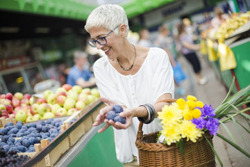 Senior woman buying fruit on market