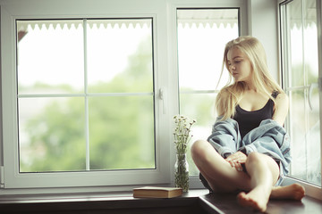 Window sitting young adult girl at home