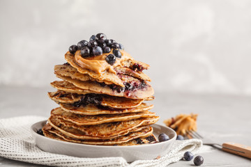 Stack vegan blueberry pancakes with peanut butter and syrup. © vaaseenaa
