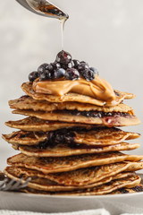 Stack vegan blueberry pancakes with peanut butter and syrup.
