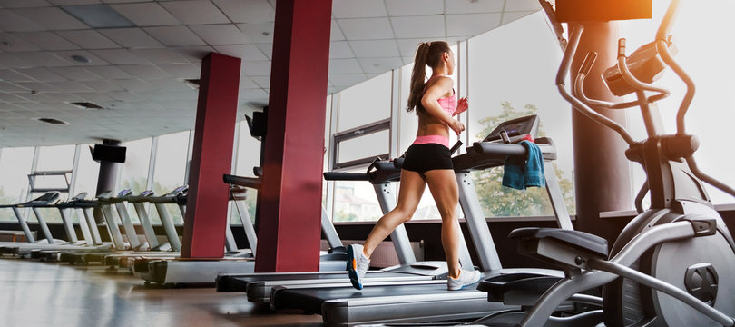 slim beautiful sporty woman running at the treadmill in the gym. Concept of cardio exercises and healthy way of life