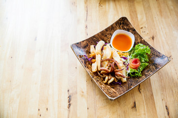 fried squids in wood plate.Steamed squid fried with salty sauce Thai food.Grilled squid and vegetable with spicy seafood sauce on  wood table.