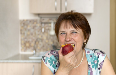 adult woman eating a peach and laughing in the room