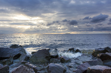 Fototapeta na wymiar surf line with boulders, Gulf of Finland at sunset, sea water, sunset sky, Russia