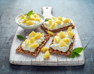 Homemade Crispbread toast with Cottage Cheese and Pineapple on white wooden board.