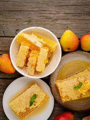 honey in honeycomb, close-up, on brown ceramic plate, on old gray wooden rustic table, top view, vertical, copy space