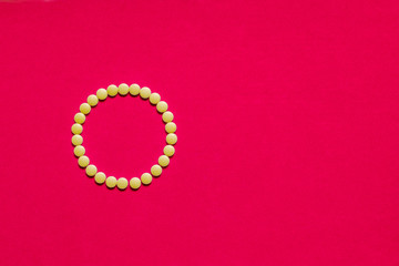 Ring of medicine pills or capsules on red background