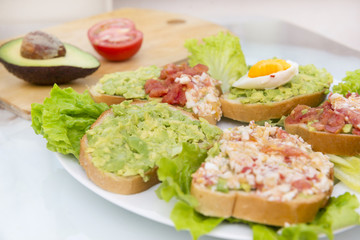 sandwiches with avocado, egg and tomato on lettuce leaves on a plate, breakfast,  a healthy snack