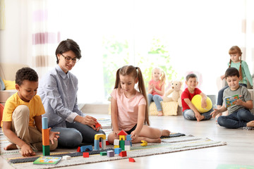 Young woman playing with little children indoors