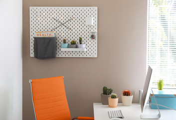 Modern workplace and pegboard with different cacti in room