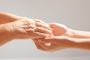 Helping hands on grey background, closeup. Elderly care concept