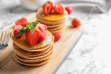 Tasty pancakes with berries on wooden board