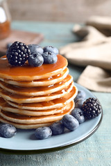 Tasty pancakes with berries and syrup on plate