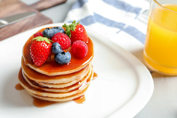 Tasty pancakes with berries and syrup on plate