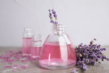 Obraz na płótnie Canvas Bottles with aromatic lavender oil on grey table
