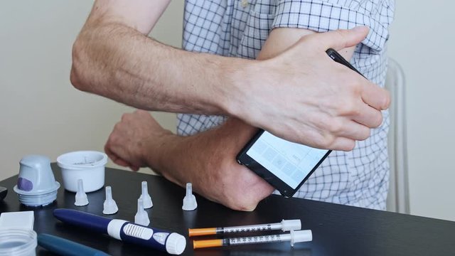 A man hands brings to the hand the smartphone for measuring glucose in the blood