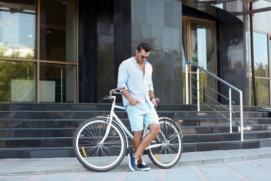 Handsome young hipster man with bicycle outdoors