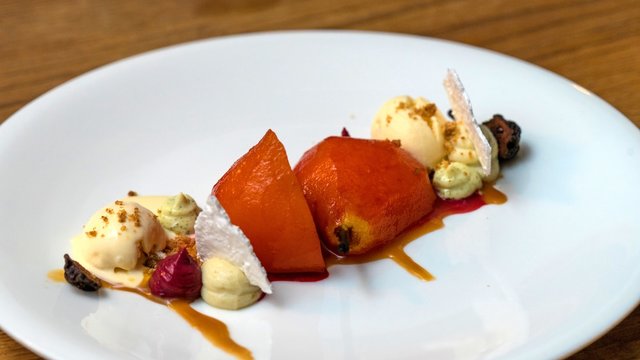 Baked pear with vanilla ice cream close-up on a plate. Cafe GRUSHA, Krasnaya Polyana