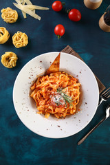 tagliatelle with tomato sauce with pouring cheese on a wooden background
