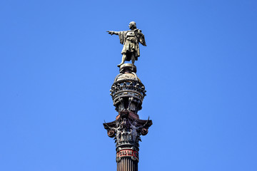 Spain, Barcelona: Detail close up of famous Columbus Monument (Monument de Colom) at the lower end of La Rambla in the city center of the Spanish town with blue sky - isolated on blue background.