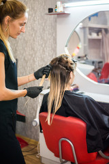 The hairdresser applies nutritious and healing components to damaged hair, applying botox to the hair, combs every strand