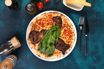 pizza with steak and cheese with olive oil on a wooden background