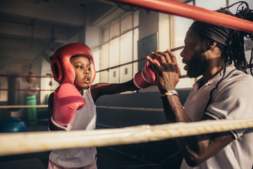 Boxing kid practicing punches with his coach - Powered by Adobe