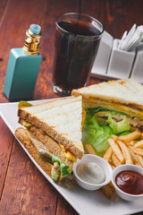 Club sandwich with french fries, and vaporizer on wooden background