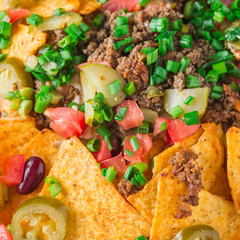 A plate of delicious nachos with jalapeno, beans and guacamole sauce