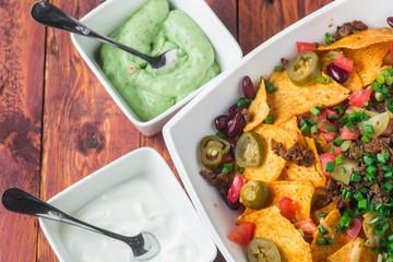 A plate of delicious nachos with jalapeno, beans and guacamole sauce