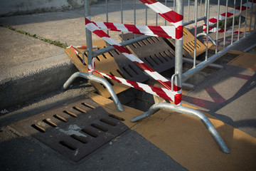 Opened Manholes in the Street and Delimited by a Red and White Ribbon before the Cleaning