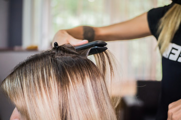 The hairdresser pulls the client hair, after washing his head, applying nutrients to the hair and drying the hair with a hair dryer, botox hair, restoring and nourishing the hair