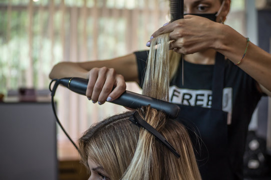 The hairdresser pulls the client hair, after washing his head, applying nutrients to the hair and drying the hair with a hair dryer, botox hair, restoring and nourishing the hair