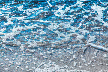 pure azure clear water with white foam on the sea on a sunny afternoon, blurry background