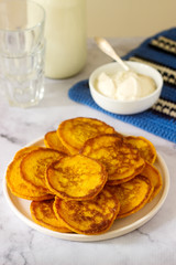 Homemade pumpkin pancakes served with sour cream on a light background.