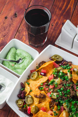 A plate of delicious nachos with jalapeno, beans and guacamole sauce