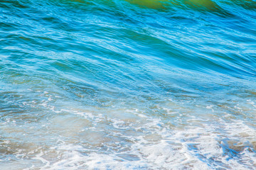 pure azure clear water with white foam on the sea on a sunny afternoon, blurry background