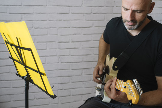 Man studying music with electric guitar at home