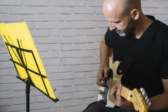 Man studying music with electric guitar at home
