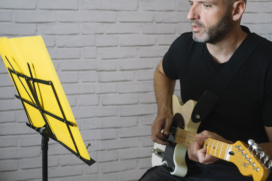Man studying music with electric guitar at home