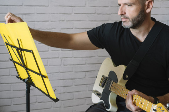 Man studying music with electric guitar at home