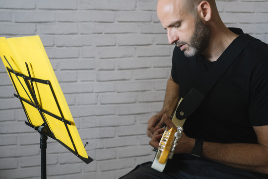 Man studying music with electric guitar at home
