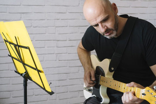 Man studying music with electric guitar at home