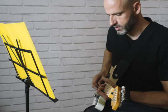 Man studying music with electric guitar at home