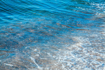 pure azure clear water with white foam on the sea on a sunny afternoon, blurry background