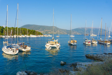 Fototapeta na wymiar Picturesque view of the port of Fiskardo with the sailing boats on sunset in Kefalonia, Greece