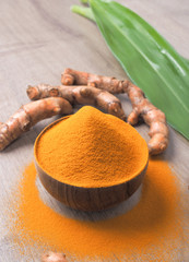 Turmeric powder in wood bowls on wooden table. Herbs