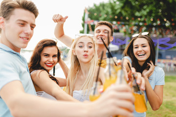 A company of good-looking friends laughing and drinking yellow c