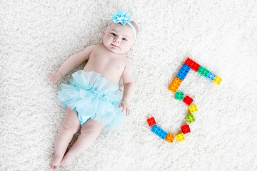 Adorable baby girl on white background wearing turquoise tutu skirt. Cute little child laughing and smiling. Happy carefree baby. Childhood, new life concept.. © Irina Schmidt