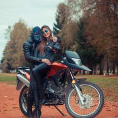 Plakat portrait of a beautiful hipster girl on a sports motorcycle with a guy in the skull mask